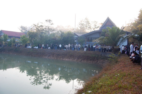 เรียงรายรอตักบาตร บริเวณด้านข้างของวัดและกุฏิที่เห็นคือกุฏิของหลวงตาผนึก.jpg